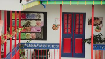 Fachada de edificio colorida con puerta roja y azul, una escalera y plantas en macetas.