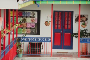 Fachada de edificio colorida con puerta roja y azul, una escalera y plantas en macetas.