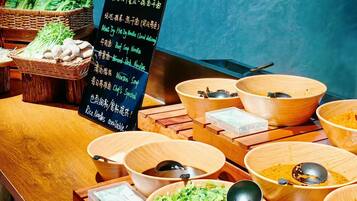 A buffet table with various dishes and a signboard with menu items in a foreign language.