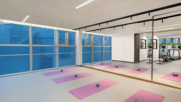 A spacious room with large windows, exercise mats, and gym equipment.