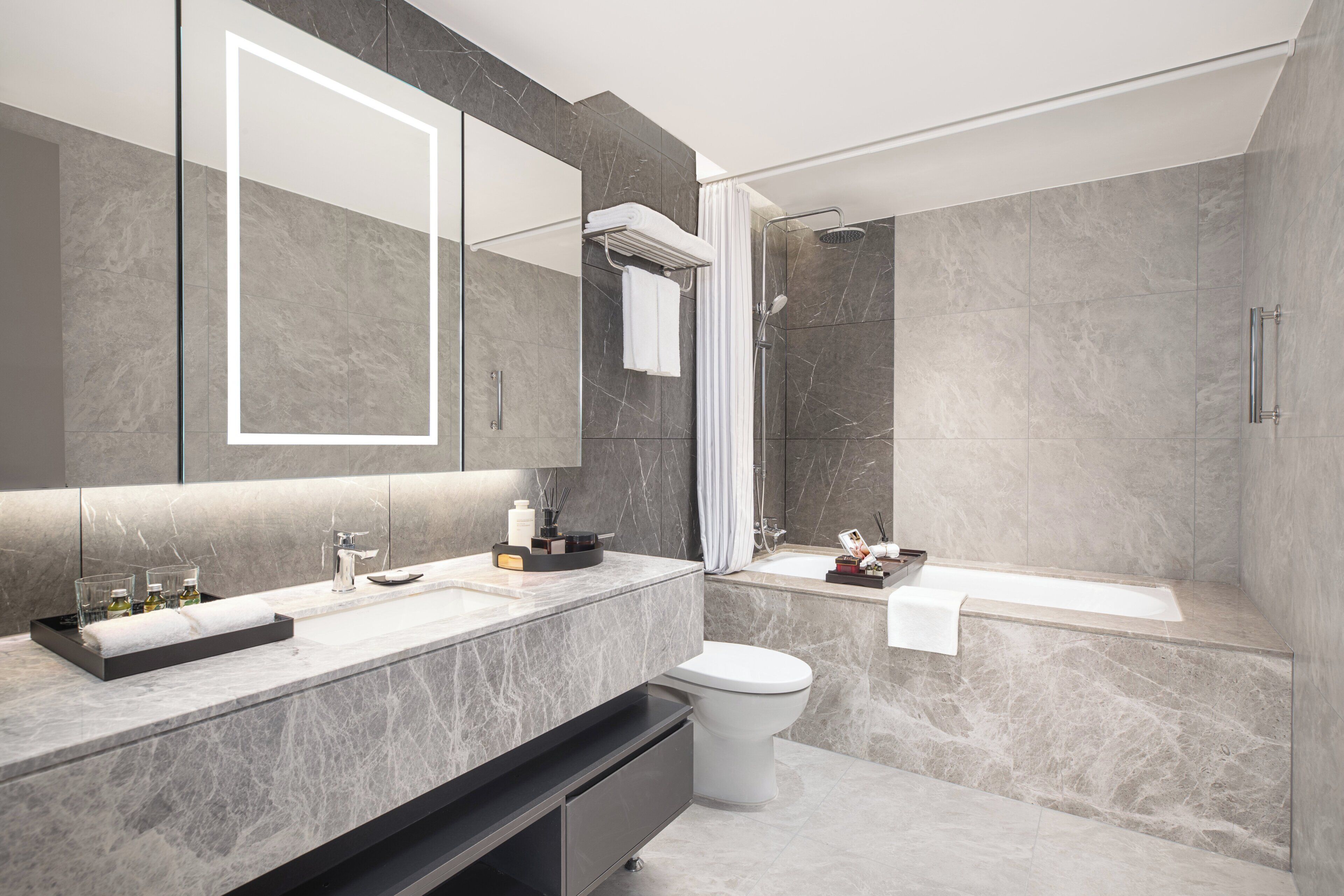 Un baño moderno con un espejo grande, un lavabo, un inodoro y una bañera.
