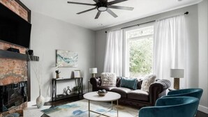 Un salon avec une cheminée, un ventilateur de plafond, un canapé et une table basse.