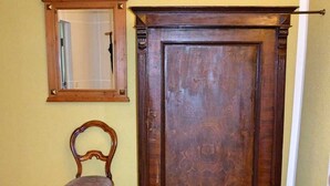 A wooden cabinet with a mirror above it and a chair in front. - Cozy vacation apartment near the Müggelsee lake (Berlin)