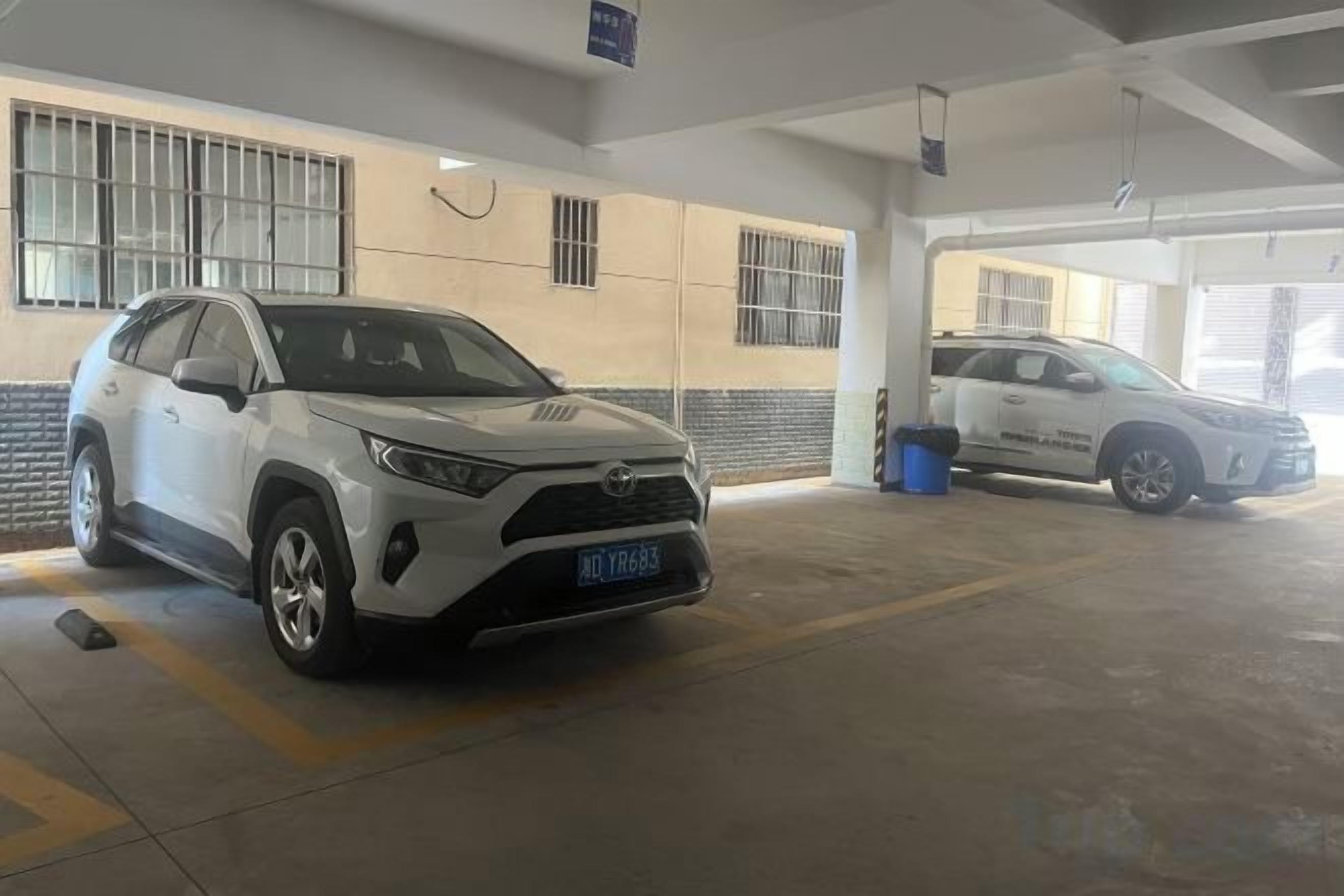 A parking garage with two white SUVs parked inside.