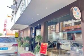 A hotel entrance with a glass facade, a red carpet, and a signboard. - Mingzhu Hotel (Gasa Airport Railway Station) (Jinghong)