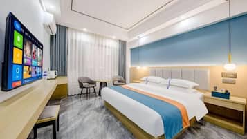 Habitación de hotel con cama, mesita de noche, escritorio, silla y televisor montado en la pared.