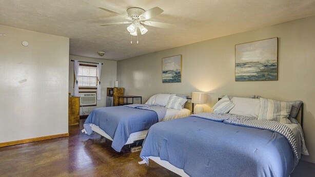 A bedroom with two beds, a ceiling fan, and artwork on the walls.