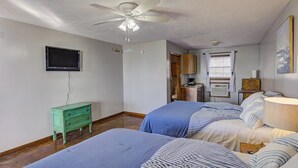 A bedroom with two beds, a ceiling fan, a television, and a small green dresser.