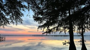 Escena tranquil·la al costat d'un llac, amb un moll que s'endinsa a l'aigua, envoltada d'arbres.