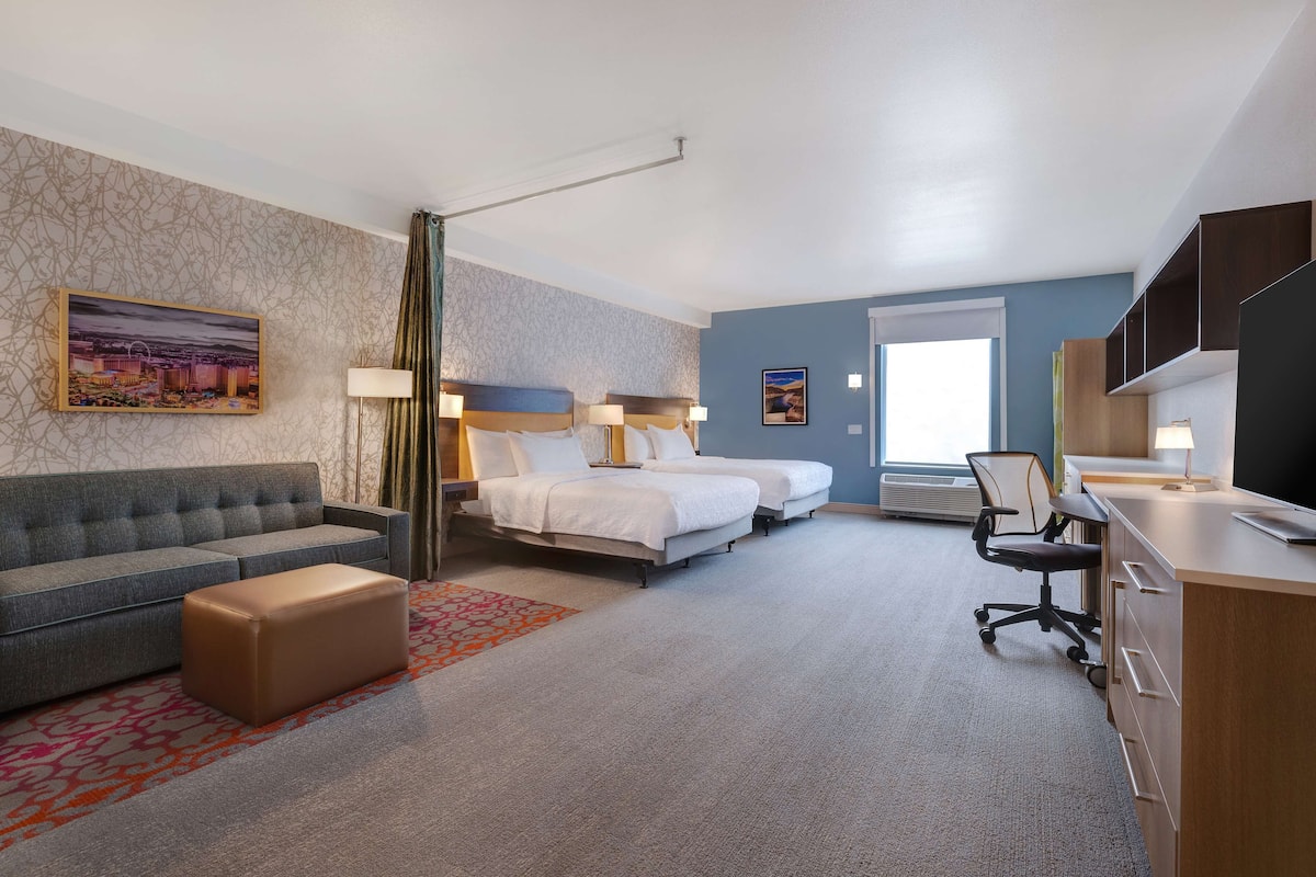Ett hotellrum med en soffa, två sängar, ett skrivbord och en stol.