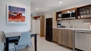 A modern kitchen with a dining area, featuring a refrigerator, microwave, and dishwasher.