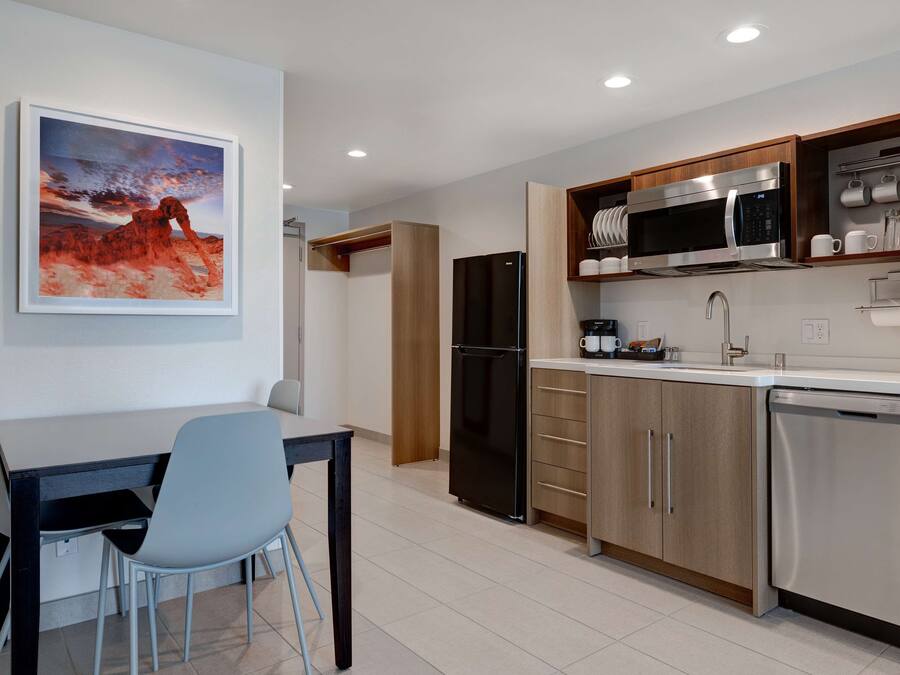 A modern kitchen with a dining area, featuring a refrigerator, microwave, and dishwasher.
