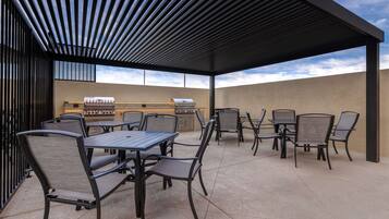 An outdoor patio with a grill, tables, and chairs.