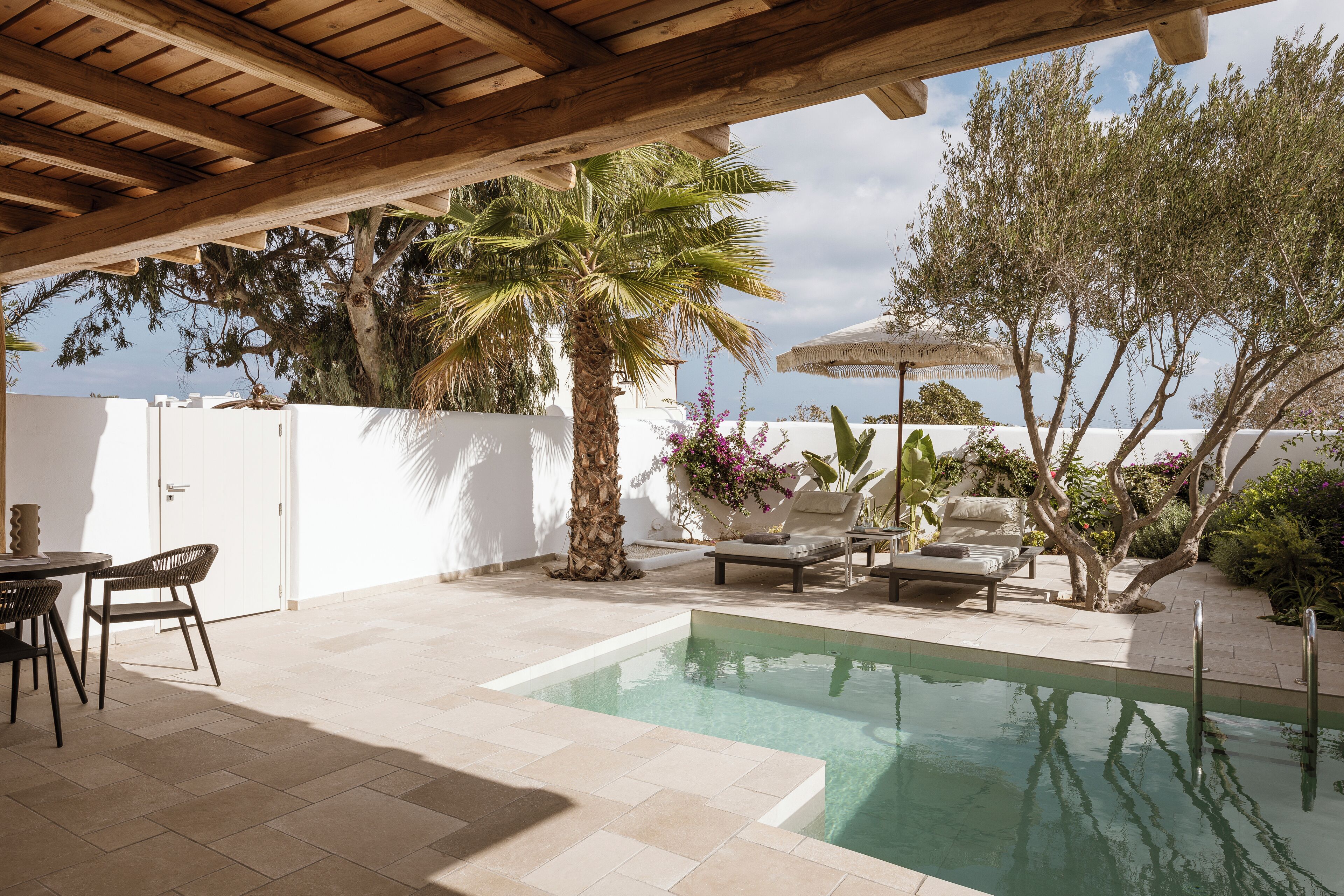 Zona de piscina con pérgola, mobiliario exterior y vista al mar.
