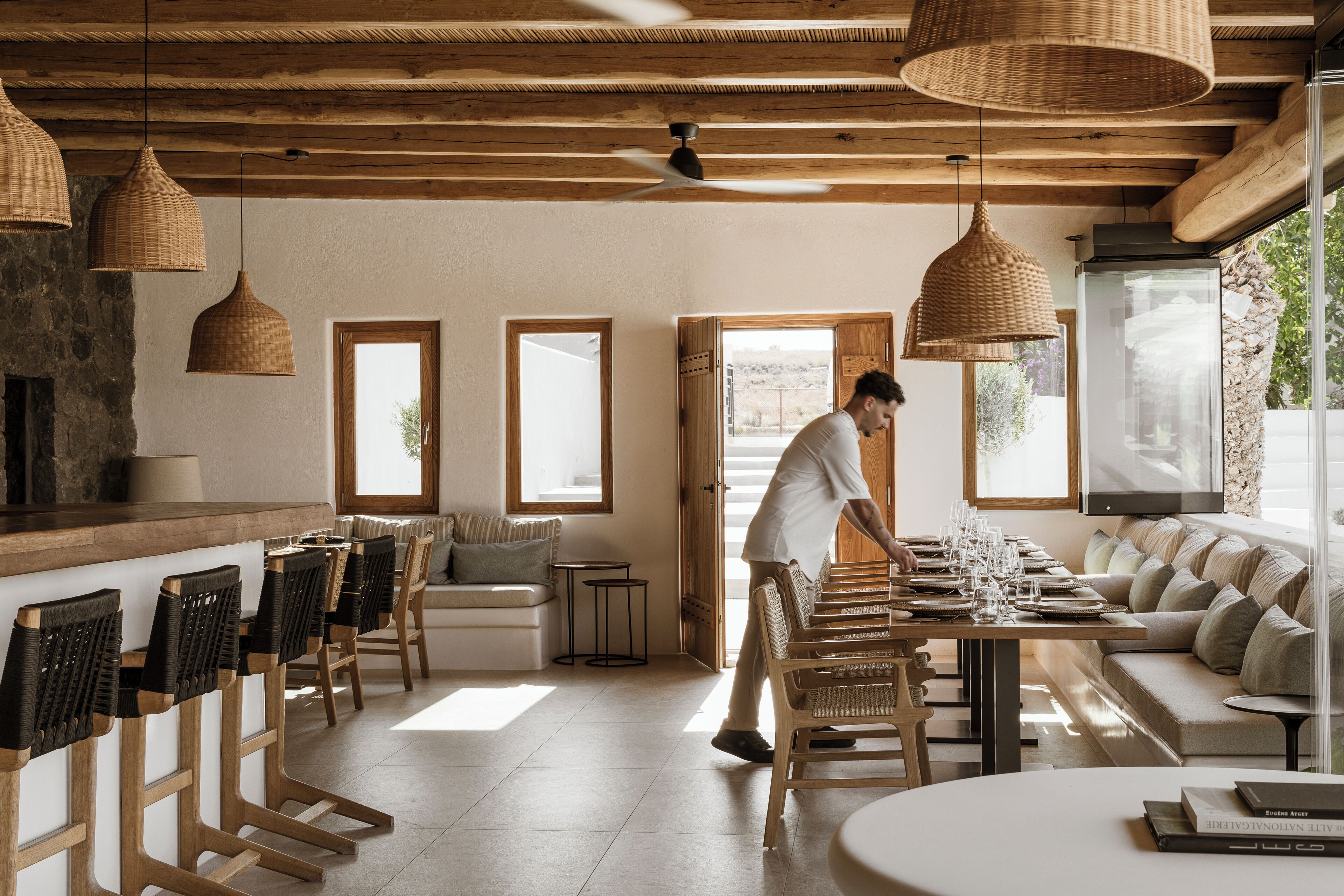 A modern kitchen with wooden beams, large windows, and a bar area with bar stools.