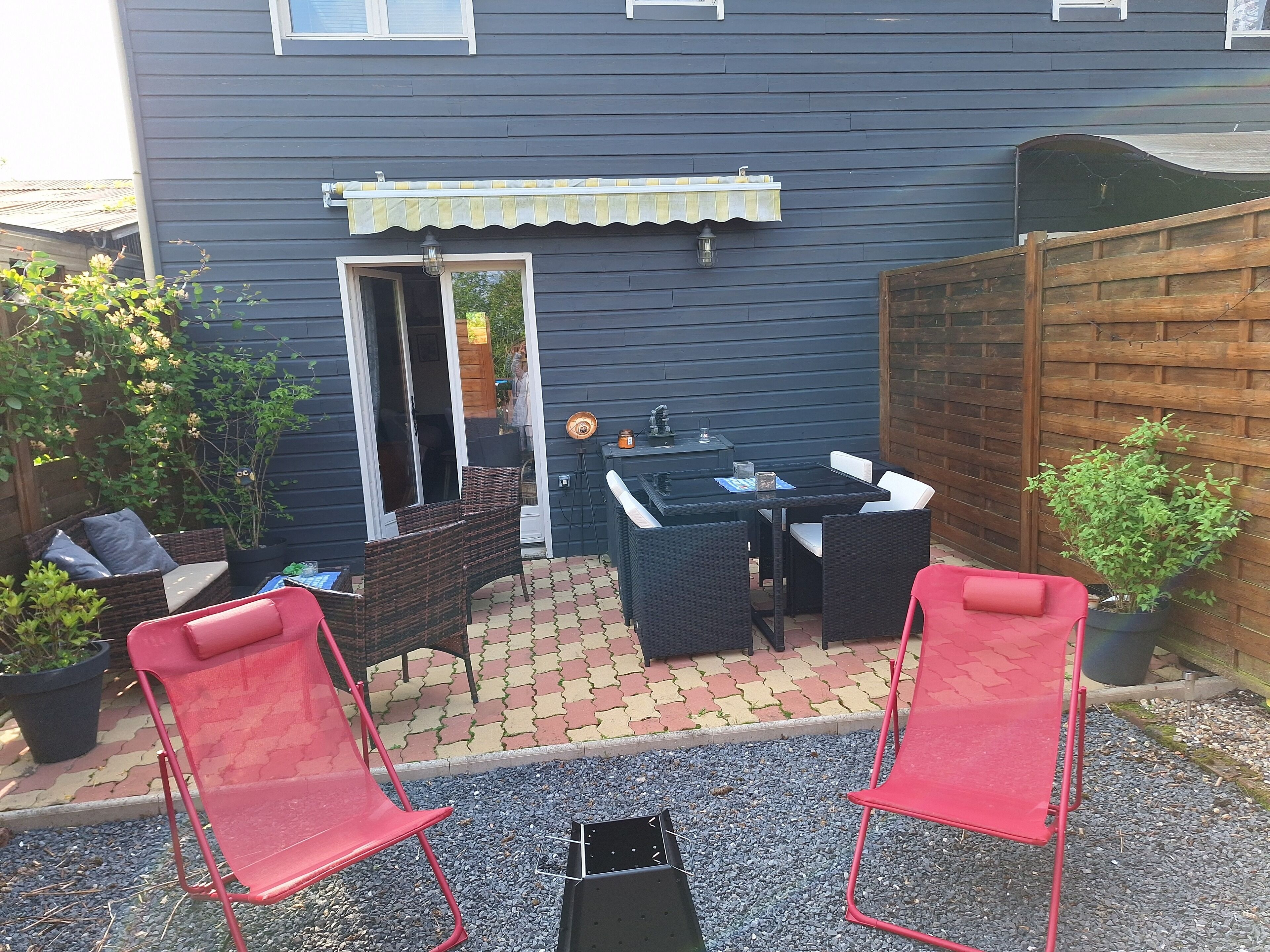 A patio with a table and chairs, a small garden, and a wooden fence.