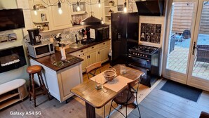 Een moderne keuken met een centraal eiland, houten vloeren en een eethoek met een tafel en stoelen.