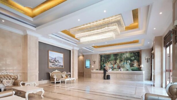 Eine geräumige Lobby mit einer Rezeption, einer Sitzecke und einem großen Gemälde an der Wand.