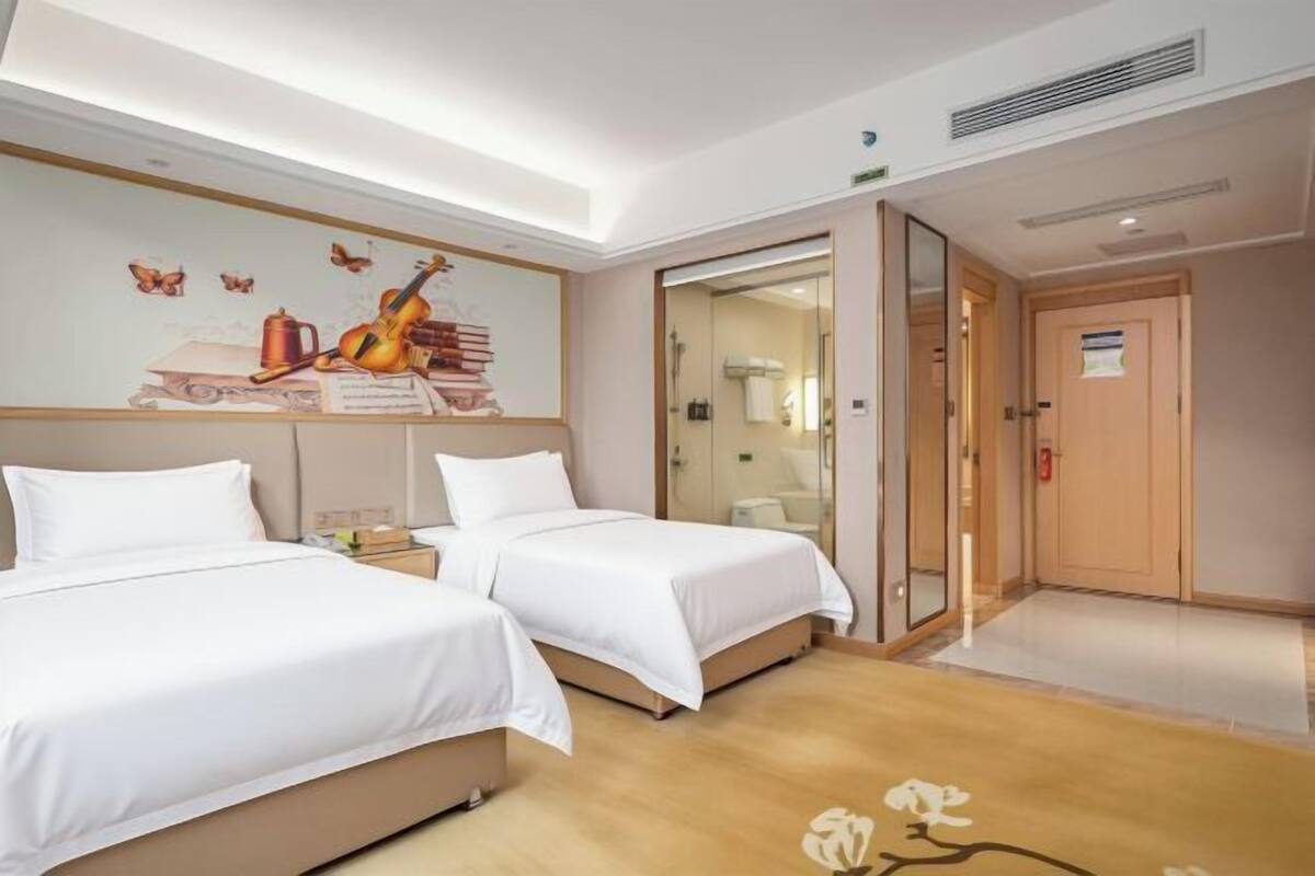 A hotel room with two beds, a mural on the wall, and a wooden floor.
