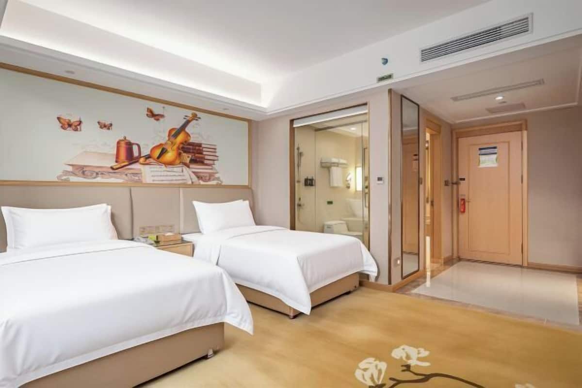 A hotel room with two beds, a mural on the wall, and a wooden floor.