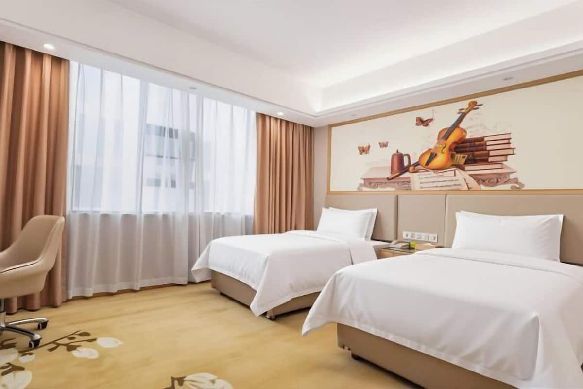 A hotel room with two beds, a chair, and a large window with curtains.