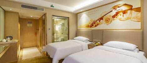 A hotel room with two beds, a large mirror, a painting, and a small desk with a telephone.