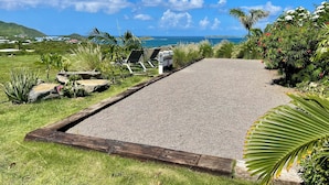 Een verhard pad naar een strand met ligbedden en uitzicht op de oceaan.