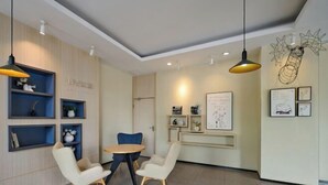 Um interior moderno com uma mesa redonda e duas cadeiras, uma estante de livros e obras de arte penduradas na parede.