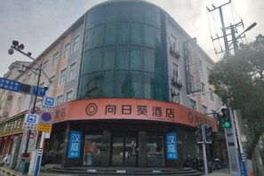 Un hotel con fachada de vidrio curva y señalización que indica que se trata del Hotel Sunflower.