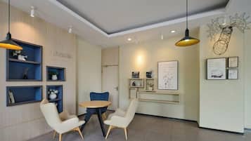 A modern interior with a round table and two chairs, a wooden cabinet with shelves, and wall-mounted artwork.
