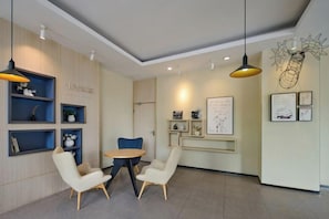 A modern interior with a round table and two chairs, a wooden cabinet with shelves, and wall-mounted artwork. - Hanting Express (Nantong Haimen Middle Jiefang Road) (Nantong)