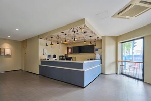 Un área de recepción con mostrador, luces de techo y un ventanal grande.