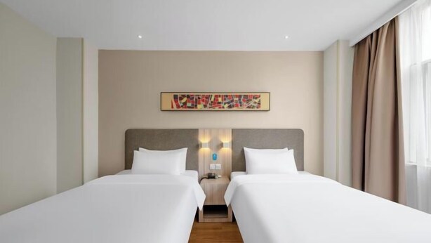 Quarto de hotel com duas camas de solteiro, esquema de cores neutras e design moderno.