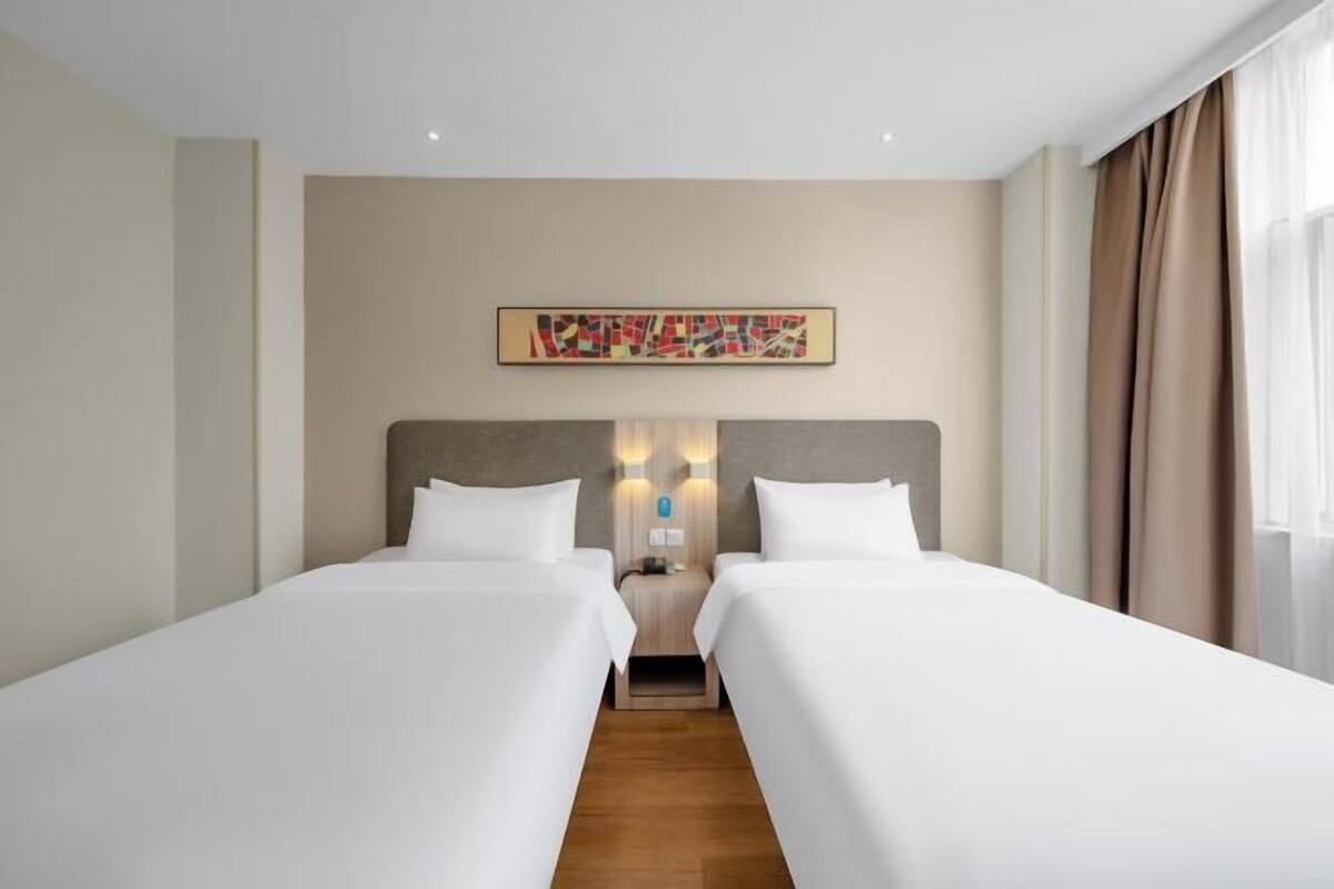 A hotel room with two single beds, a neutral color scheme, and a modern design.