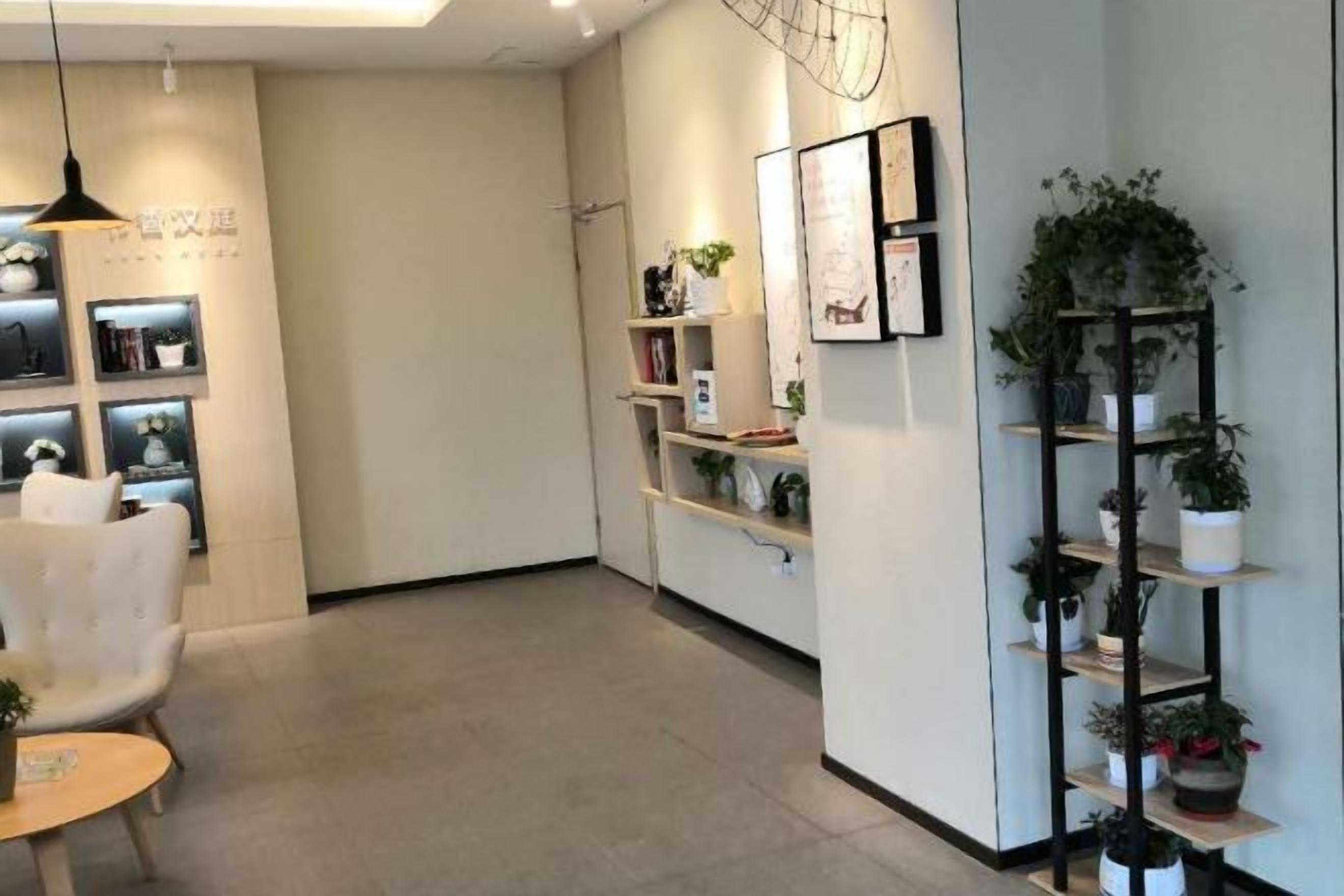 A modern interior with a reception desk, shelving with plants, and framed artwork.
