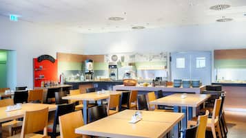 A modern cafe with wooden tables and chairs, a counter with a coffee machine, and a menu board.