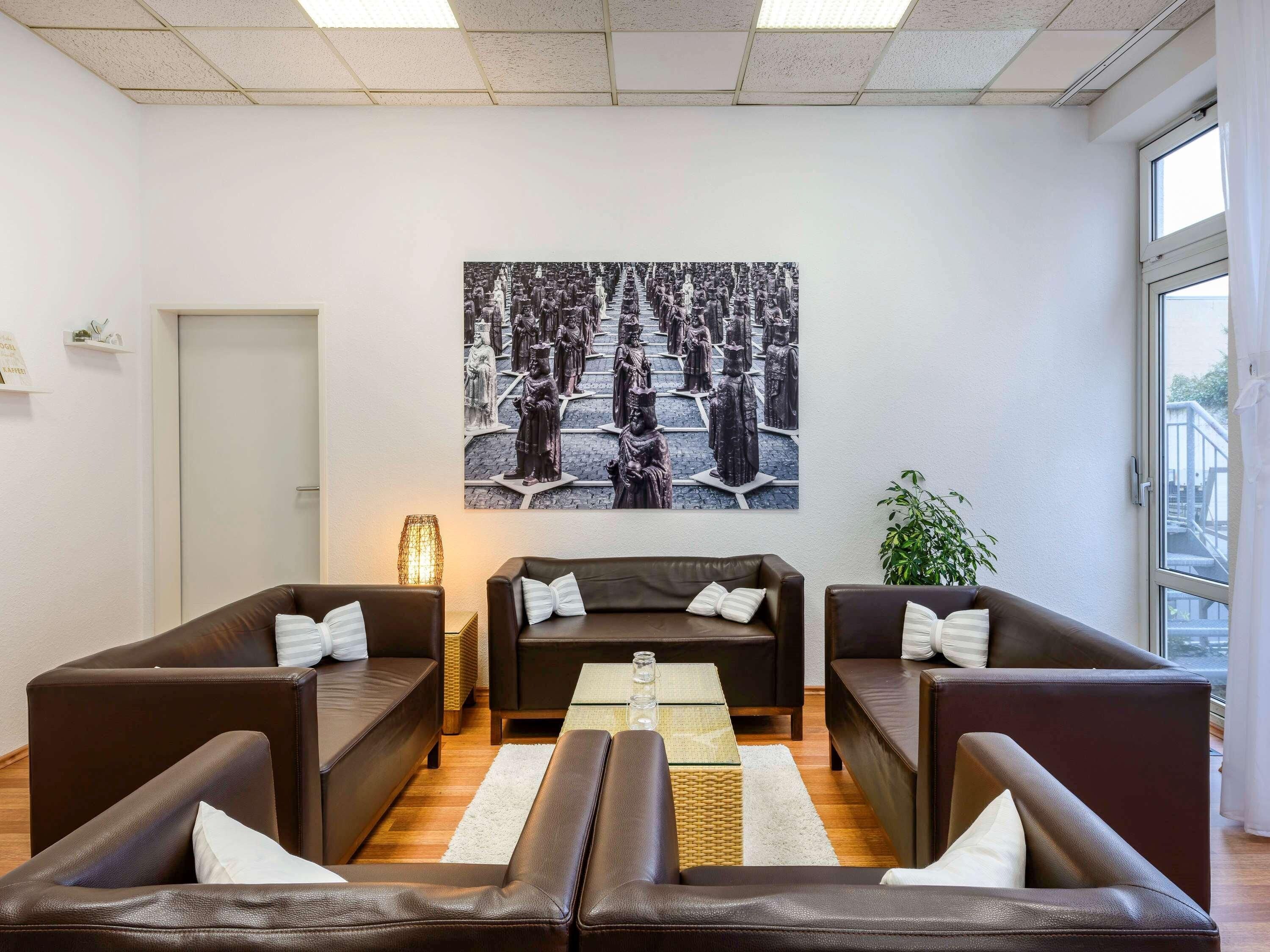 Una sala de estar moderna con sofás de cuero, una mesa de centro y una gran obra de arte en blanco y negro en la pared.