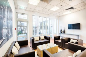 Et moderne loungeområde med lædersofaer, et glastæppe og et fladskærms-tv på et stativ.