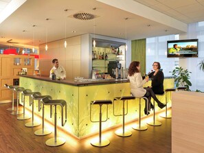 Eine moderne Bar mit Bartresen, Hockstühlen und einem Fernsehbildschirm.