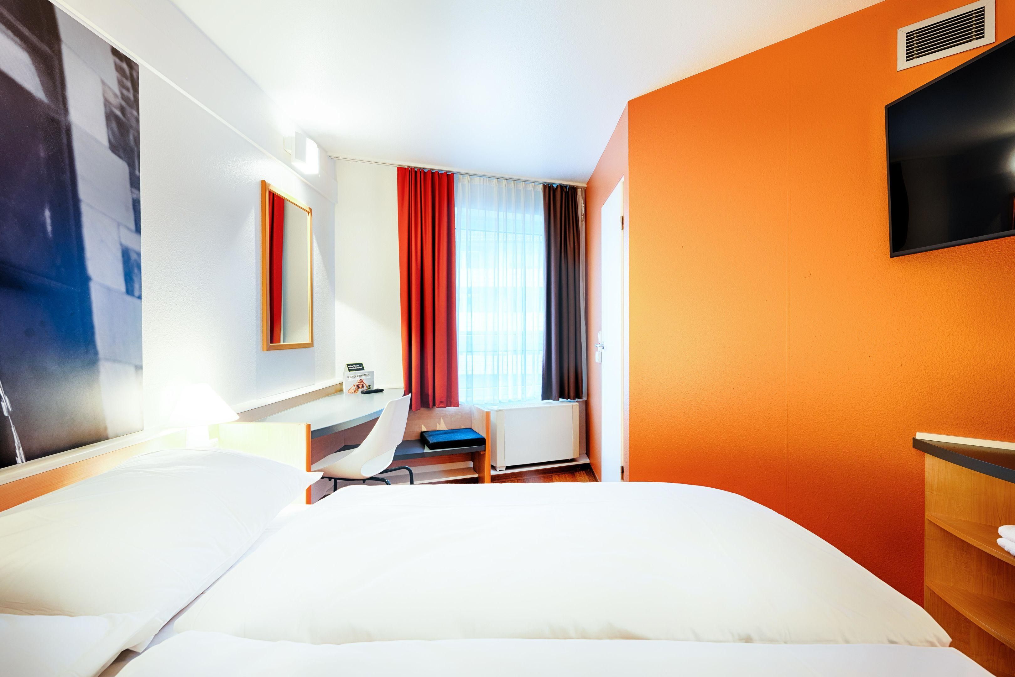 A hotel room with a bed, a desk, and a chair.