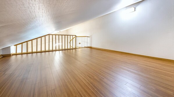Un amplio ático con piso de madera y techo inclinado.