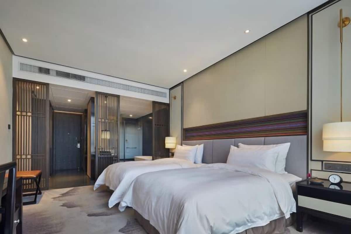 Una habitación de hotel moderna con dos camas, un escritorio y un espejo grande.