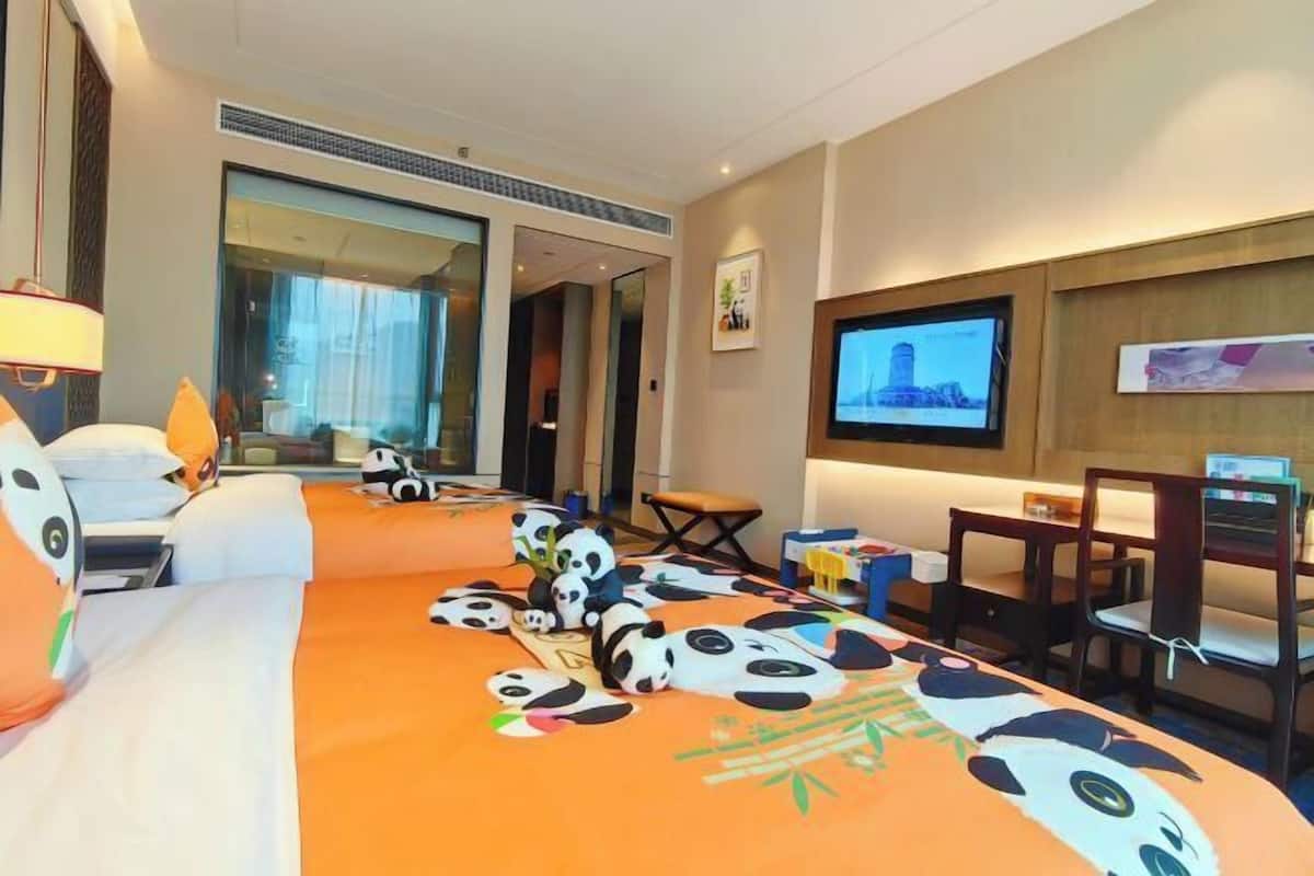 Una habitación de hotel con cama, televisión, escritorio y silla.