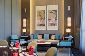 Une chambre d’hôtel moderne équipée d’un canapé, d’une table à manger et de deux lampes fixées au mur.