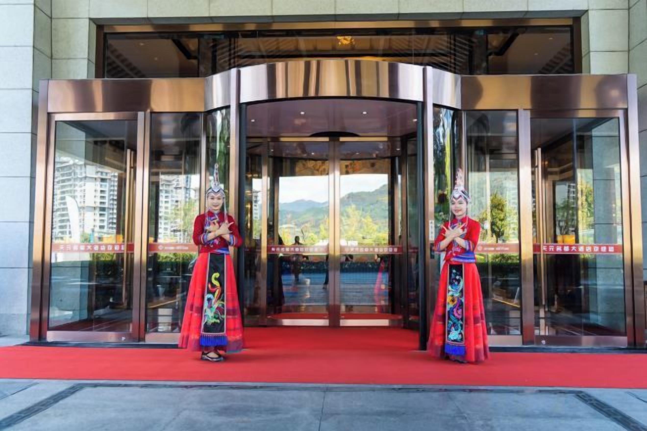 A hotel entrance with a revolving door and a red carpet.