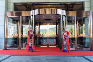 L’entrée d’un hôtel, avec une porte tournante et un tapis rouge.