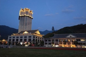 A traditional building with a modern skyscraper in the background, surrounded by a landscaped area. - Tianyuan Mingyue Hotel (Jingning)