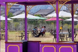 An outdoor seating area with tables and chairs under a purple canopy structure. - Tianyuan Mingyue Hotel (Jingning)