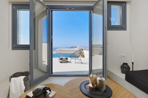 A modern room with a large sliding glass door leading to a balcony with a pool and outdoor furniture.