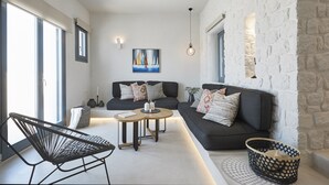 En moderne stue med en sofa, en lænestol, et rundt sofabord og en kurv.